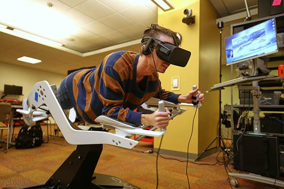 在沉浸式媒体实验室里，一名学生在虚拟现实机里的照片