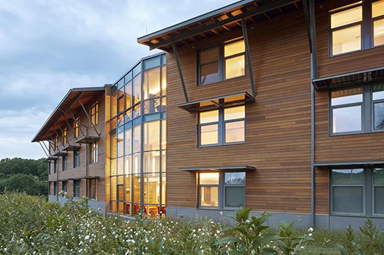 波胆网站伊甸园大厅校园的果园大厅, 有大窗户、木墙板和屋顶太阳能板的建筑.